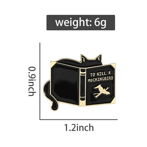 Detail view of black cat enamel pin with To Kill a Mockingbird book title and bird design