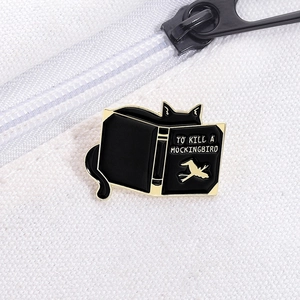 Detail of black cat enamel pin on white canvas with To Kill a Mockingbird text