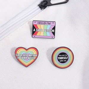 Detailed macro view of three rainbow enamel pins with supportive text on white canvas bag