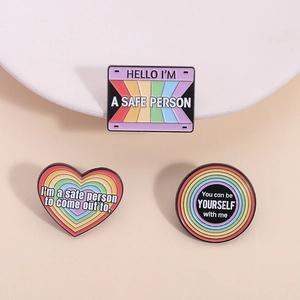 Close-up of rainbow enamel pins with inclusive text and polished zinc alloy edges