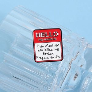 Detail of Inigo Montoya movie quote enamel pin on a clear glass edge with blue background
