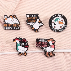 Set of five cute white goose enamel pins with funny English phrases on pink denim fabric