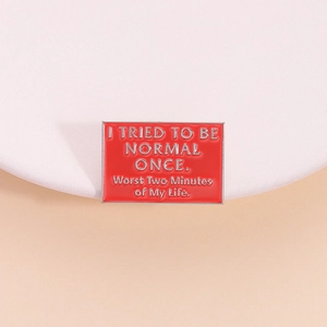 Rode emaille rechthoekige broche met humoristische tekst op een minimalistische standaard