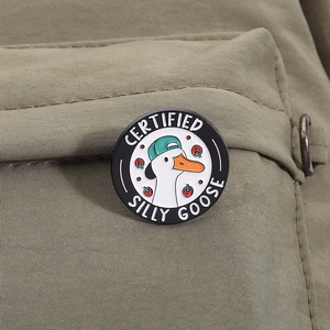 Close-up of a Certified Silly Goose enamel pin on a green fabric backpack strap