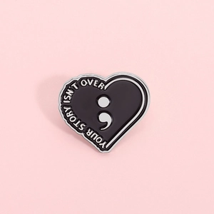 Épinglette coeur noir avec texte YOUR STORY ISN'T OVER et symbole point-virgule