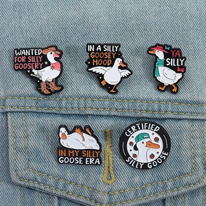 Close-up of five cute white goose enamel pins styled on a blue denim jacket pocket