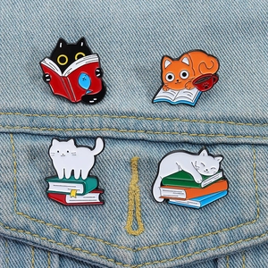 Set of four cute cartoon cat and book enamel pins displayed on a denim jacket pocket