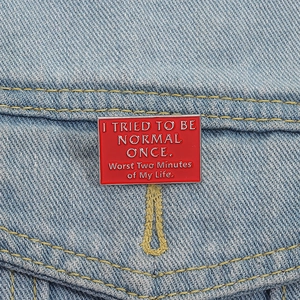 Detailopname van rode emaille speld met grappige tekst op lichtblauwe denim achtergrond