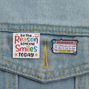 Détail de broches en émail avec citations inspirantes sur tissu en jean bleu