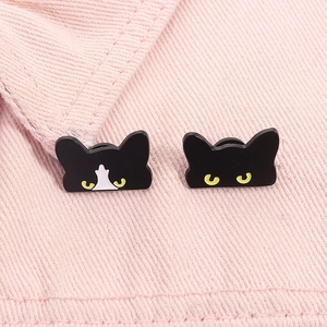 Set of two cute black and tuxedo cat enamel pins on pink denim fabric background