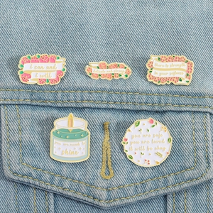 Detail of five motivational floral enamel pins attached to a blue denim jacket pocket