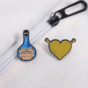 Detail of Shrek-inspired green heart and potion enamel pins pinned on a white canvas bag