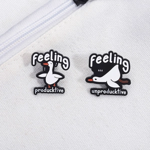 Détail de pin's en émail oie blanche avec slogans humoristiques sur fond de tissu blanc