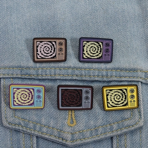 Detail of five colorful retro television enamel pins on a blue denim jacket pocket