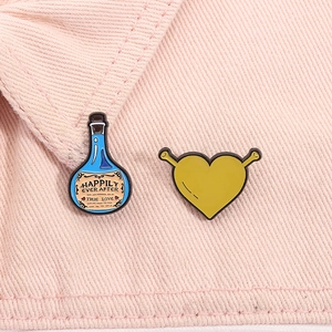 Macro view of Shrek heart pin and potion bottle brooch on pink denim fabric surface
