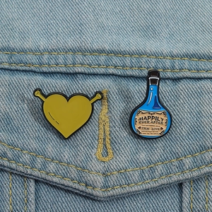 Close-up of Shrek-inspired heart and potion enamel pins on a blue denim jacket