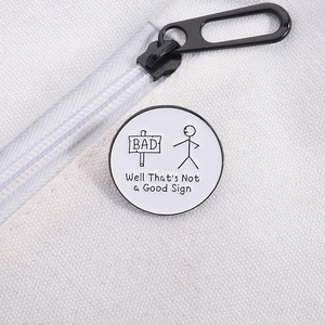 Detail of round enamel pin with stickman and 'Not a Good Sign' text on white canvas bag