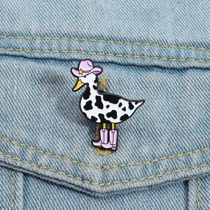 Detail of cow-print duck enamel pin with pink cowboy hat on denim jacket pocket