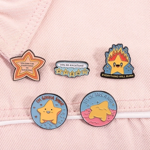 Set of five cartoon enamel star pins on pink denim fabric featuring creative slogans