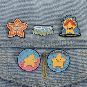 Set of five colorful star enamel pins with motivational quotes on denim fabric