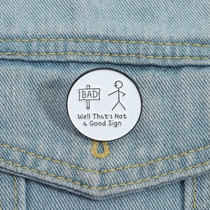 Funny stickman enamel pin on denim jacket featuring a bad sign pun illustration