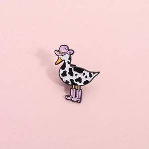 Cartoon duck enamel pin with cow pattern print, pink cowboy hat and boots on pink card