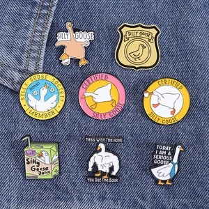Set of eight cartoon silly goose enamel pins on blue denim fabric background detail