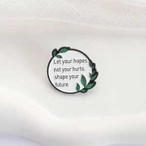 Pin's émaillé minimaliste avec citation inspirante et bordure de feuilles sur fond blanc