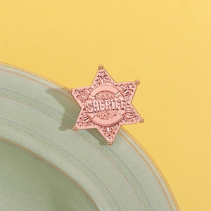 Detailed close-up of rose gold Sheriff badge star with vintage floral engravings