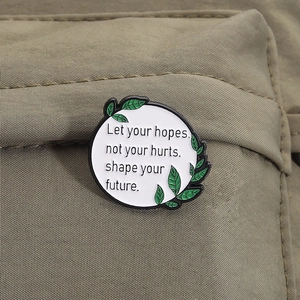 Gros plan d'un pin's émaillé blanc rond avec citation inspirante sur un sac à dos en toile