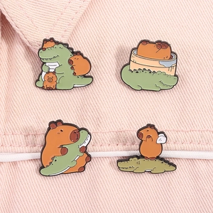 Close-up of four cute capybara and crocodile enamel pins on pink denim fabric background
