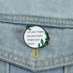 Détail de la broche en émail ronde avec citation sur une poche en jean bleu clair
