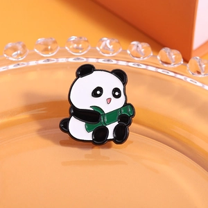 Macro shot of cute cartoon panda enamel pin with green bamboo detail on orange background