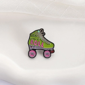 Green roller skate enamel pin with pink wheels and This Is How I Roll slogan engraving