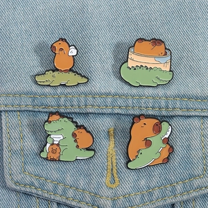 Close-up of four cute capybara and crocodile enamel pins on blue denim fabric