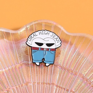 Macro view of cartoon tooth enamel pin with ORAL HIGH JEAN text on a rainbow tray