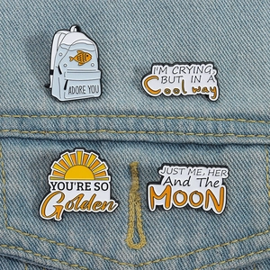 Detailed close-up of four cute quote enamel pins pinned on a blue denim jacket