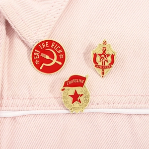 Vista dettagliata delle spille smaltate KGB URSS su uno sfondo di tessuto rosa strutturato