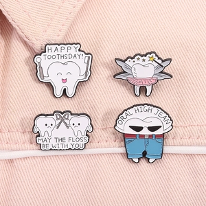 Detail of four cute cartoon enamel pins with dental health themes on pink denim cloth