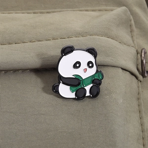 Close-up of a cute giant panda enamel pin holding green bamboo on an olive canvas bag