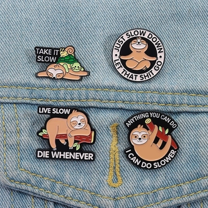 Detailed view of four sloth enamel pins on denim fabric with funny motivational quotes