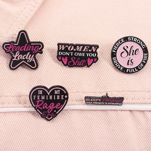 Detail von 5 Emaille-Broschen mit rosa Empowerment-Schriftzügen auf Denim-Hintergrund