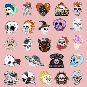 Set of 25 skull enamel brooches in dark Halloween styles on pink background