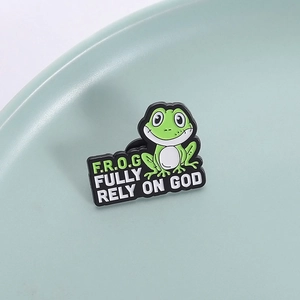 Vue macro de l'épingle émaillée grenouille avec texte Fully Rely On God sur céramique