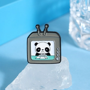 Détail d'un pin's panda émaillé en forme de téléviseur vintage sur une pierre minérale