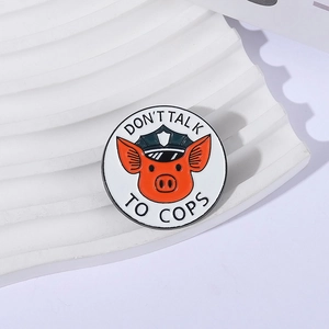 Detail of round enamel pig badge with 'Don't Talk to Cops' text on white display