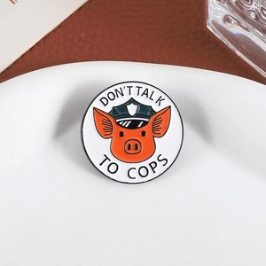 Detail of round enamel pig badge with Don't Talk to Cops text on a ceramic plate