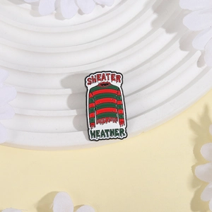 Classic red and green striped horror movie sweater enamel pin on white display stand