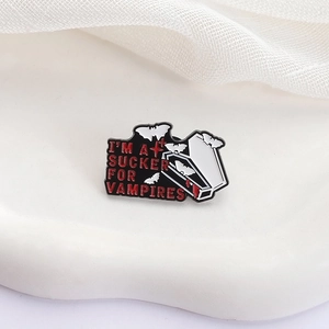 Macro shot of vampire coffin enamel pin with red gothic text and bat details