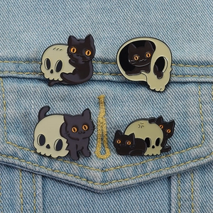 Détail de quatre épinglettes de chat noir et crâne sur le tissu d'une veste en jean